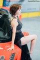 A woman sitting on top of a red sports car.