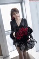 A woman in a black dress holding a bunch of red roses.