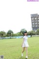 A woman in a white dress is walking on a grassy field.