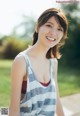 A young woman in a striped tank top smiles at the camera.