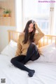 A woman sitting on a bed wearing black tights.