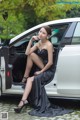 A woman in a black dress sitting in the back of a white car.