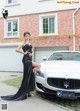 A woman in a black dress standing next to a white car.