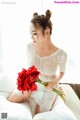 A woman in a white dress holding a bouquet of red flowers.