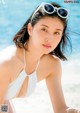 A woman in a white bikini laying on the beach.