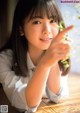 A young woman sitting at a table with a plant in her hand.