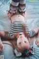 A woman laying on top of a bed wearing a black and white striped outfit.