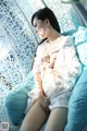 A woman in a white dress sitting on a blue chair.