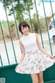 A woman standing in front of a green fence.