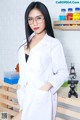 A woman in a lab coat and glasses posing for a picture.