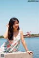 A woman sitting on a concrete wall by the water.