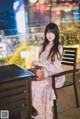 A woman sitting on a bench in a city at night.