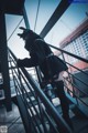 A woman in a black outfit is standing on a metal railing.