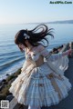 A woman in a white dress standing on a pier by the ocean.