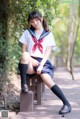 A woman in a school uniform sitting on a bench.