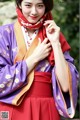 A woman wearing a purple and red kimono and a red scarf.