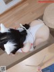 A woman in a white and black cat costume is laying on the floor.