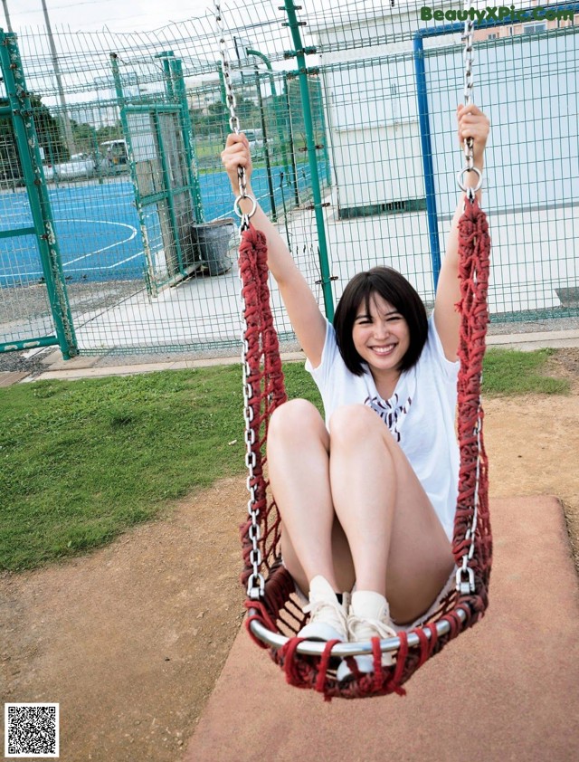 A woman sitting on a swing in a park.