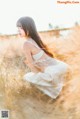 A woman in a white dress sitting in a field.