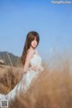 A woman in a white dress standing in a field.