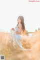 A woman in a white dress sitting in a field.