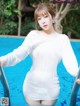 a woman in a white dress standing next to a swimming pool