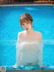 A woman in a white shirt is sitting in a pool.