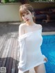 a woman in a white dress standing next to a pool