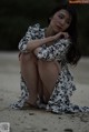 A woman sitting on the sand with her legs crossed.