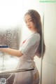 A woman in a white shirt is standing in a shower.