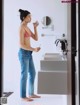 A woman standing in front of a bathroom mirror holding a cell phone.