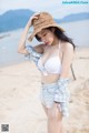 A woman in a straw hat is standing on the beach.
