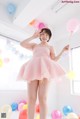 A woman in a pink dress holding a bunch of balloons.