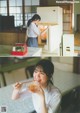 A woman holding a bowl of food in front of an open refrigerator.