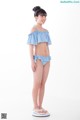 A young girl in a blue and white bikini standing on a scale.