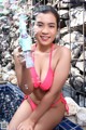 A woman in a pink bikini sitting in a pool with bubbles.