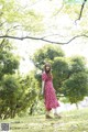 A woman in a red dress standing in a park.