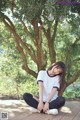 A woman sitting on a wooden deck next to a tree.