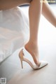 A close up of a woman's legs in high heels on a bed.