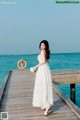 A woman in a white dress standing on a wooden pier.