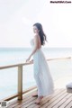 A woman in a white dress standing on a wooden deck.