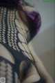 A close up of a woman wearing a fishnet bodysuit.