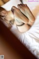 A woman in fishnet stockings laying on a bed.