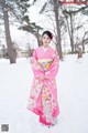 A woman in a pink kimono standing in the snow.