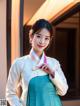 A woman in a blue and white hanbok posing for a picture.