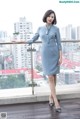 A woman in a blue dress standing on a balcony.