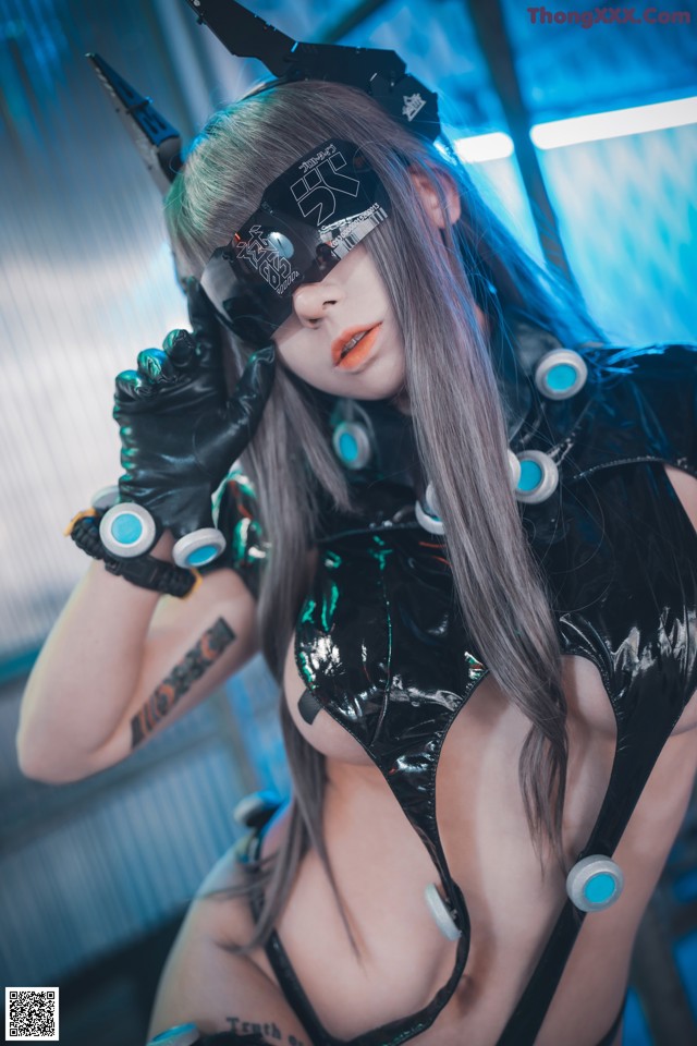 A woman in a black latex outfit holding a pair of gloves.